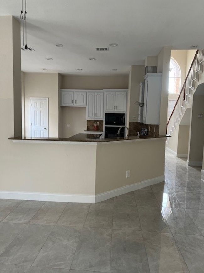 Kitchen featuring wall oven, tasteful backsplash, baseboards, white cabinets, and dark countertops | Image 10