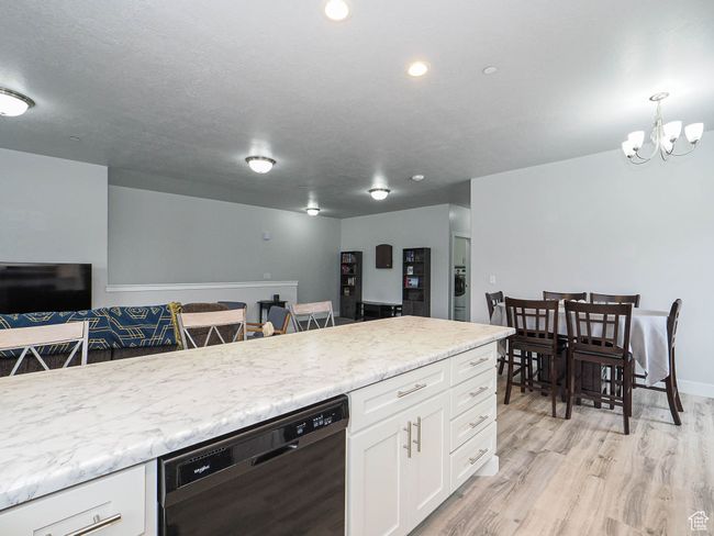 Kitchen featuring a chandelier, light wood finished floors, dishwasher, open floor plan, and white cabinets | Image 15