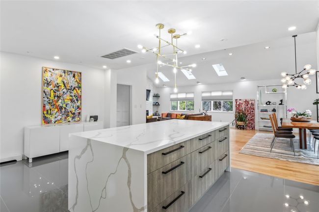 Kitchen featuring modern cabinets, a chandelier, a large island, hanging light fixtures, and vaulted ceiling | Image 10