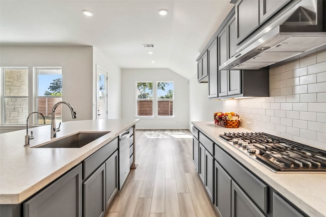 Kitchen featuring under cabinet range hood, appliances with stainless steel finishes, light countertops, recessed lighting, and decorative backsplash | Image 16