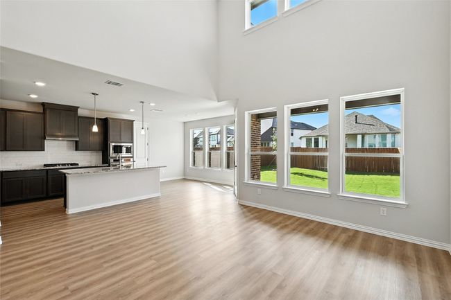 Kitchen featuring stainless steel appliances, open floor plan, light wood-style floors, backsplash, and a high ceiling | Image 9
