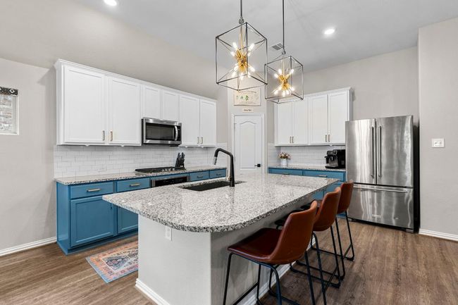 Kitchen with stainless steel appliances, a sink, blue cabinetry, dark wood finished floors, and white cabinetry | Image 10