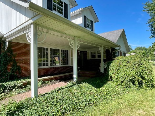view of property exterior featuring a porch and brick | Image 5