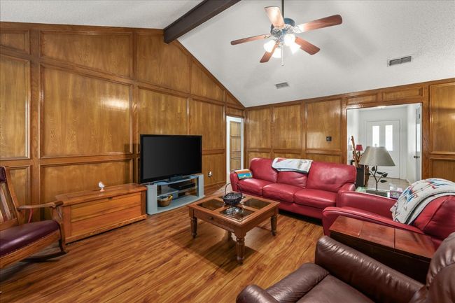 Living room featuring light wood-style floors, wooden walls, and a ceiling fan | Image 7