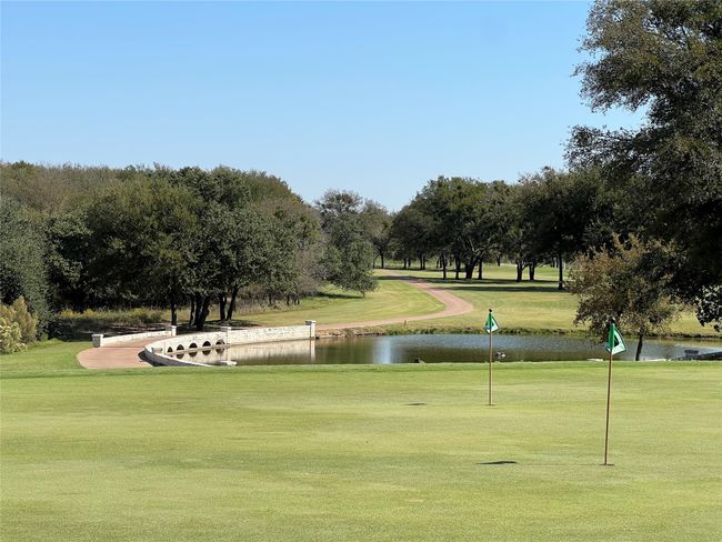 View of property's community featuring a lawn, a water view, view of golf course, and view of scattered trees | Image 6