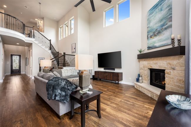 Living room with ceiling fan, wood finished floors, plenty of natural light, a high ceiling, and stairs | Image 10