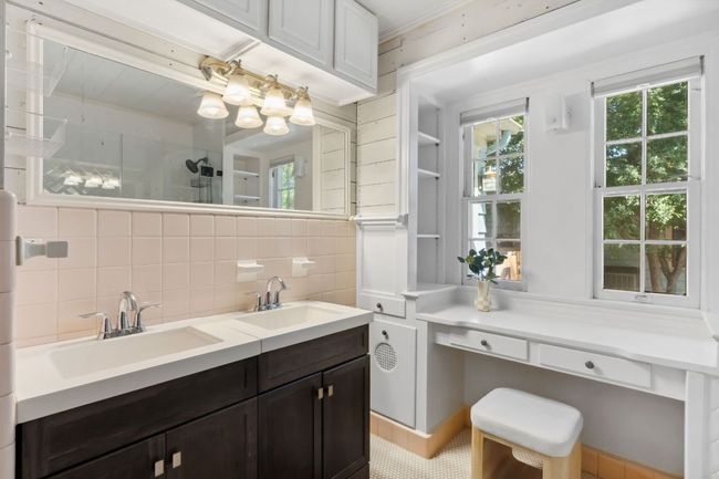 The bathroom has loads of character with vintage tile, shiplap walls, and a built in dressing table. | Image 10