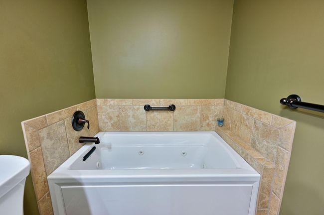 The tub has a ceramic surround and oil-rubbed bronze hardware. | Image 51