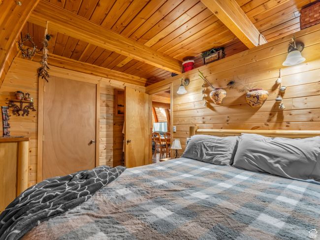 Bedroom featuring a wood ceiling with exposed beams and wood walls | Image 11