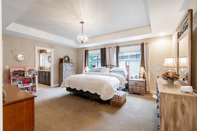 Bedroom featuring a tray ceiling, light carpet, baseboards, and a chandelier | Image 17