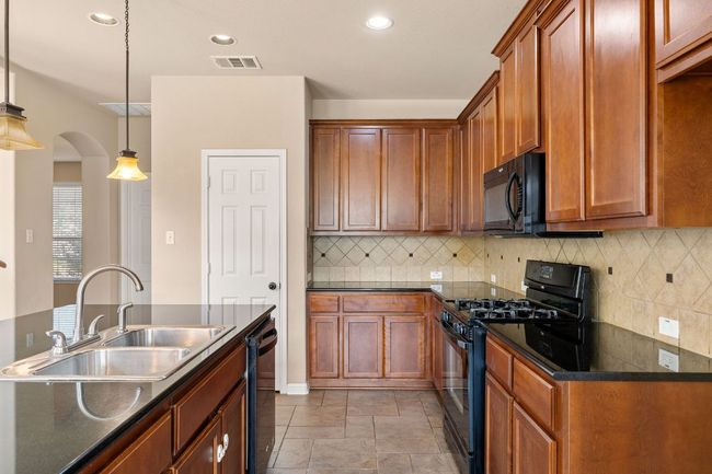 Warm wood tones, black granite and applicances along with a generously sized pantry | Image 14