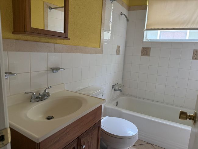 Bathroom with shower / bathtub combination, vanity, tile walls, a textured wall, and decorative backsplash | Image 19