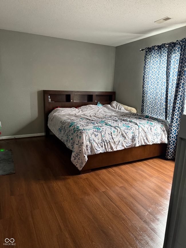 bedroom with wood finished floors and a textured ceiling | Image 6