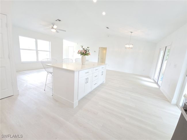 Kitchen featuring light wood-type flooring, lofted ceiling, a chandelier, a ceiling fan, and a breakfast bar | Image 16