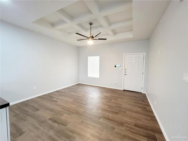 Unfurnished room with ceiling fan, wood finished floors, coffered ceiling, baseboards, and beam ceiling | Image 18