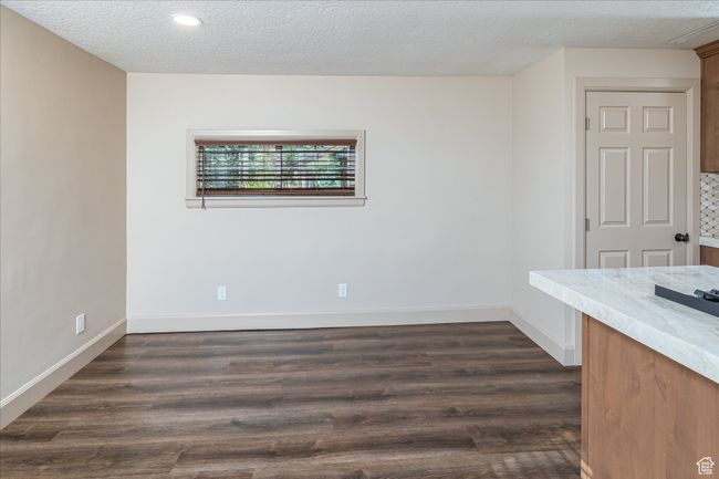 Empty room with a textured ceiling, dark wood-style floors, and recessed lighting | Image 22