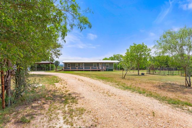View of front of property featuring dirt driveway, a carport, metal roof, and covered porch | Image 36