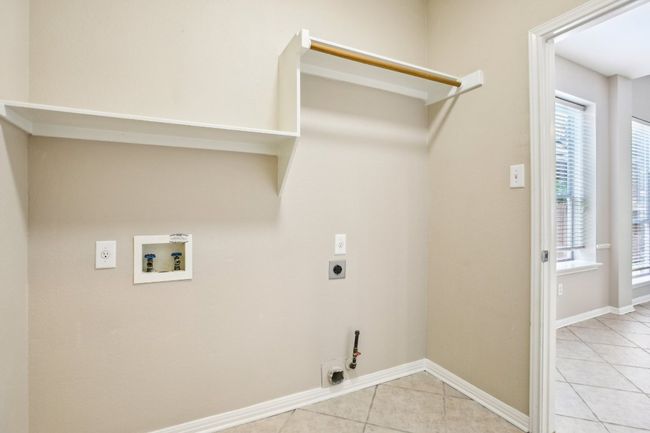 Laundry room featuring hookup for an electric dryer, hookup for a washing machine, light tile patterned flooring, hookup for a gas dryer, and baseboards | Image 14