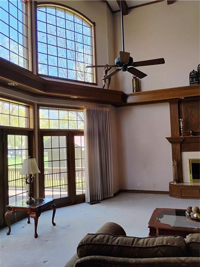 Carpeted living room featuring a high ceiling and a ceiling fan | Image 22