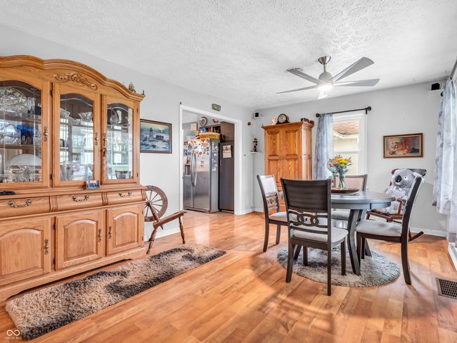 dining room with a textured ceiling, ceiling fan, light wood-type flooring, and baseboards | Image 8