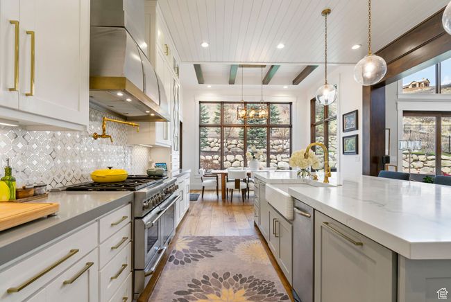 Kitchen featuring an inviting chandelier, a sink, wall chimney range hood, light wood-type flooring, and high end stainless steel range oven | Image 28