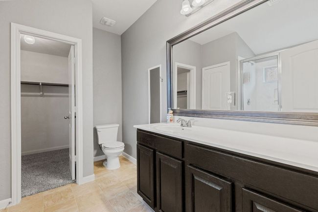 Full bathroom with a walk in closet, a shower stall, vanity, toilet, and baseboards | Image 10