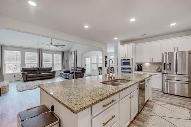 Kitchen featuring stainless steel appliances, a sink, arched walkways, light wood-style floors, and white cabinetry | Image 14