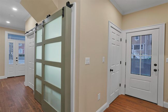 Laundry space with glass paneled barn doors. To the left is a coat closet for the front entry. | Image 18