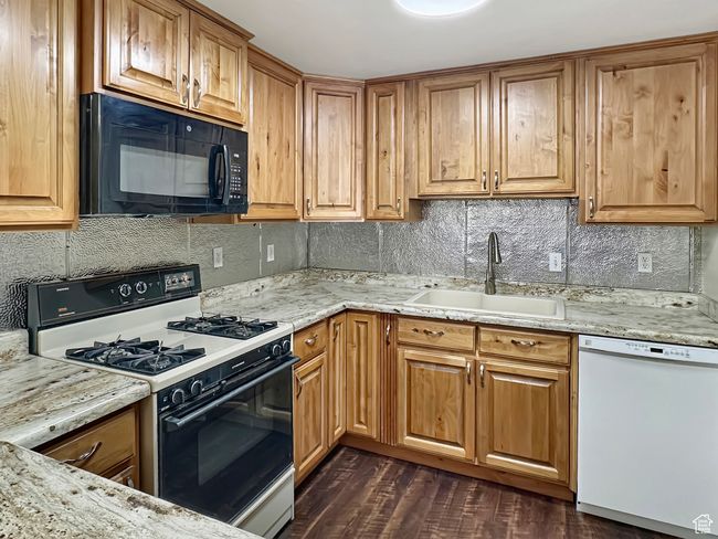 Kitchen featuring black microwave, range with gas cooktop, dishwasher, a sink, and tasteful backsplash | Image 6