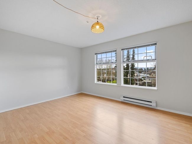 Empty room with baseboards, baseboard heating, and wood finished floors | Image 12