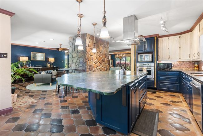 Kitchen with open floor plan, dark countertops, black appliances, island range hood, and blue cabinets | Image 20