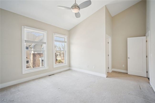 Carpeted empty room with visible vents, a ceiling fan, baseboards, and high vaulted ceiling | Image 23