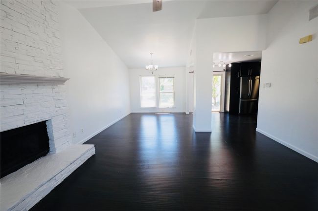 living room featuring a chandelier, dark wood finished floors, lofted ceiling, a fireplace, and ceiling fan | Image 9