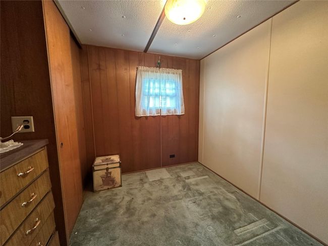 Bedroom featuring wood walls and a textured ceiling | Image 9