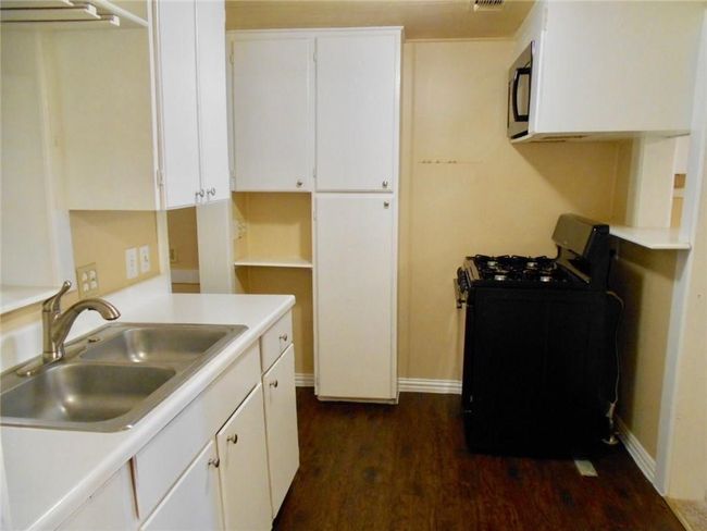 Kitchen featuring black appliances, dark wood-type flooring, white cabinets, and light countertops | Image 4
