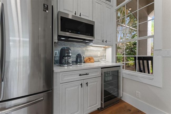 Indoor bar featuring stainless steel appliances, beverage cooler, backsplash, dark wood-type flooring, and baseboards | Image 12