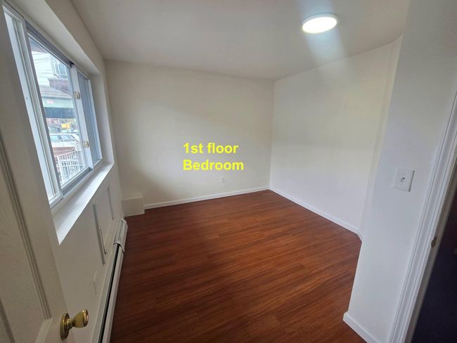 Spare room with dark wood-style flooring, a baseboard radiator, and baseboards | Image 8