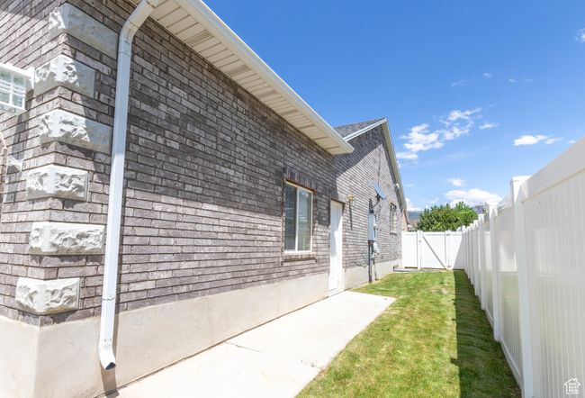 View of property exterior featuring brick siding, a patio, and a gate | Image 22