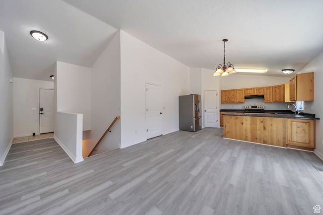 Kitchen with lofted ceiling, appliances with stainless steel finishes, dark countertops, light wood finished floors | Image 4