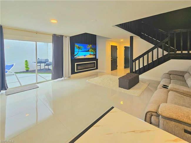 Tiled living room featuring baseboards, a glass covered fireplace, recessed lighting, and stairs | Image 10