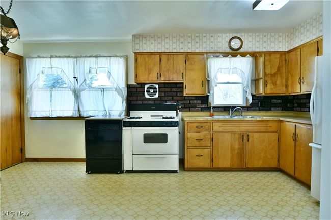 Kitchen with light floors, brown cabinets, a sink, and white appliances | Image 17