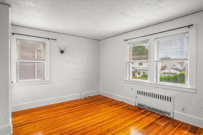 Unfurnished room featuring hardwood / wood-style floors, radiator, and a textured ceiling | Image 11