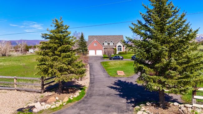 Cape cod house with a mountain view, driveway, a front lawn, a garage, and fence | Image 10