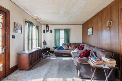 Carpeted living room with a textured ceiling, plenty of natural light, and wooden walls | Image 2