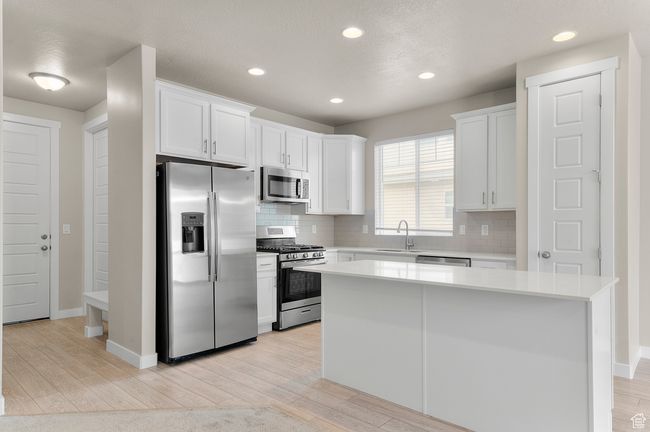 Kitchen with appliances with stainless steel finishes, decorative backsplash, light wood-style flooring, and a sink | Image 15