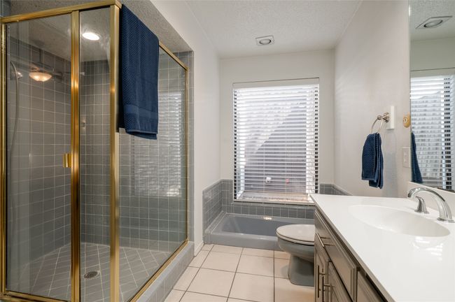 Full bath with a textured ceiling, a stall shower, vanity, and tile patterned floors | Image 20