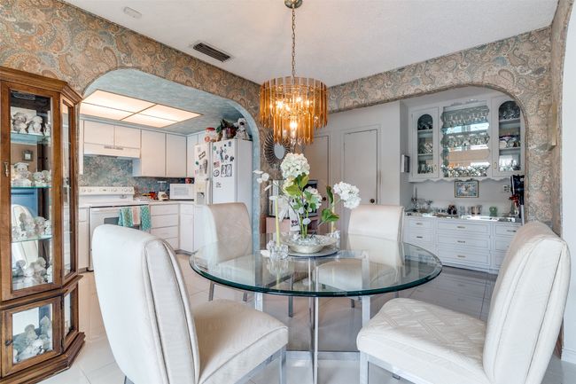 Dining space featuring a chandelier, arched walkways, light tile patterned floors, and wallpapered walls | Image 9