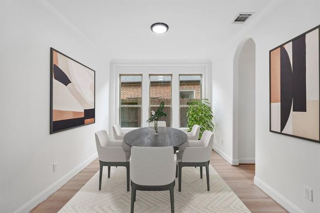 The elegant formal dining room, located next to the kitchen, features expansive windows that fill the space with natural light, stunning vinyl flooring, and the perfect ambiance for hosting unforgettable gatherings. *Virtually Staged* | Image 7
