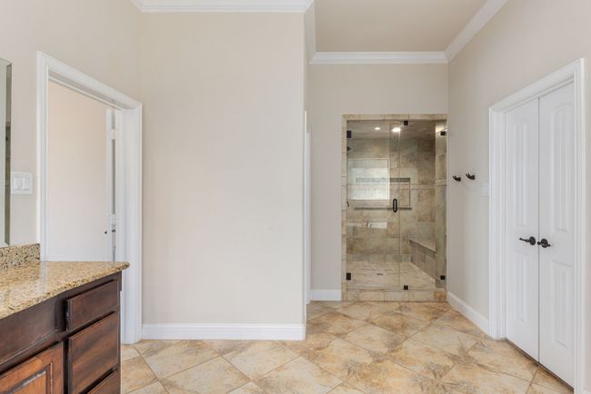Bathroom featuring vanity, baseboards, a shower stall, and crown molding | Image 26