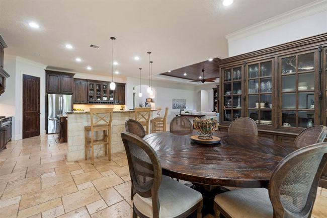 This desirable open concept design keeps sightlines open and makes entertaining effortless. Crown molding, warm wood paneling, arched openings, and Travertine flooring add to the high-end feel of the home. | Image 22